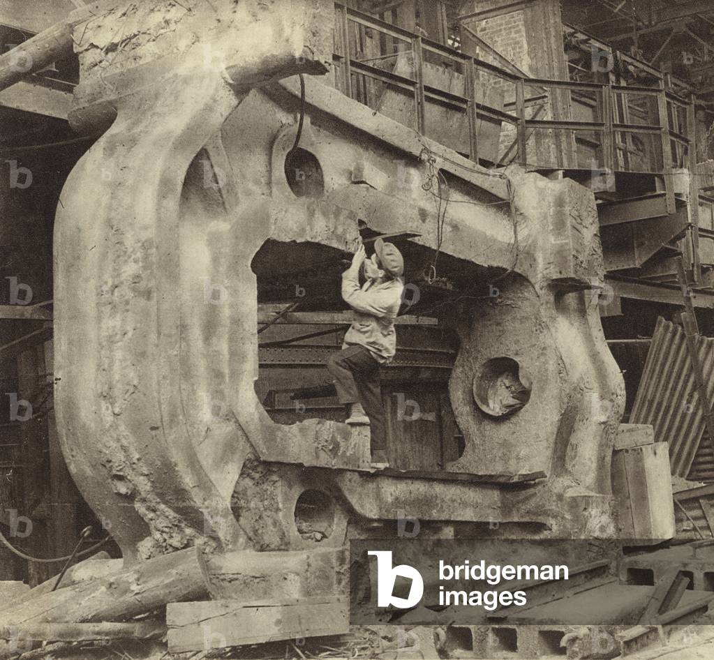 A labourer working on a 120-ton metal block, created by moulding in the Kramatorsk metallurgical plant, Ukraine, USSR, 1930 (b/w photo)