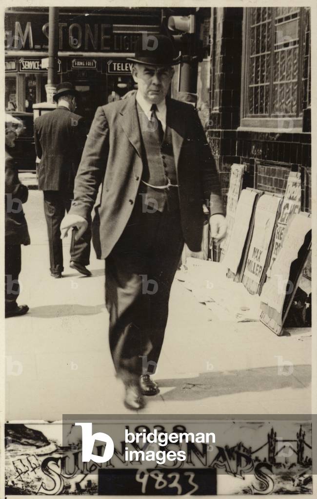 Man in a bowler hat walking along a street, 1938 (b/w photo)