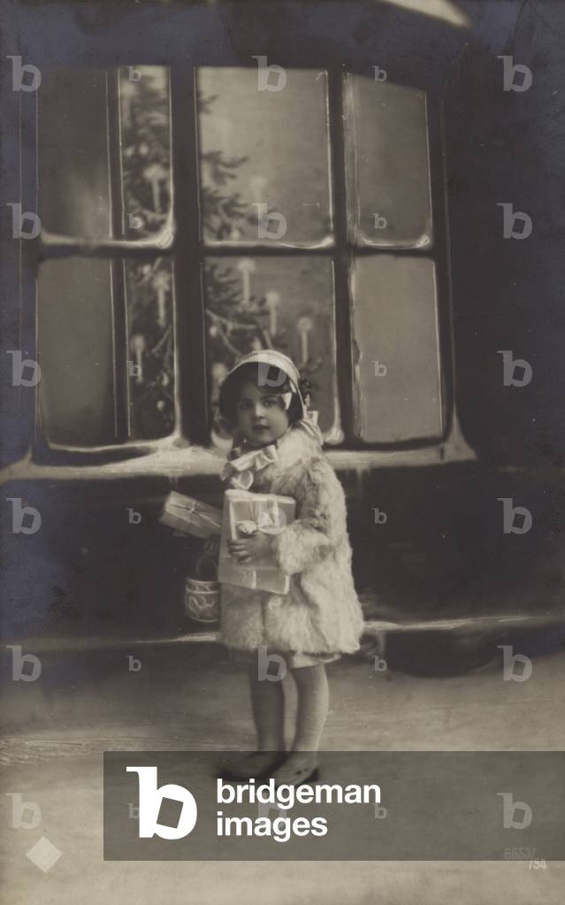 A child with Christmas presents, early 20th Century (b/w photo)