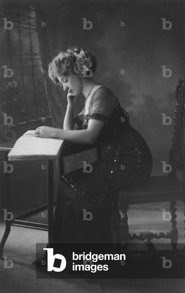 Woman reading a book at a table (b/w photo)