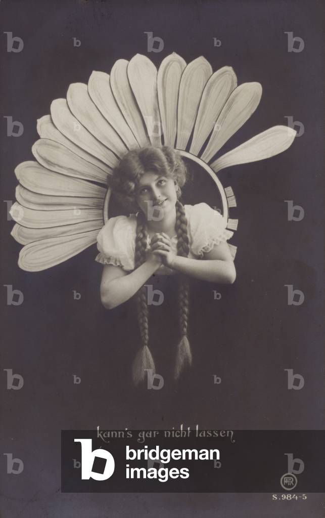 A young woman with long plaits sticks her head through a flower (b/w photo)