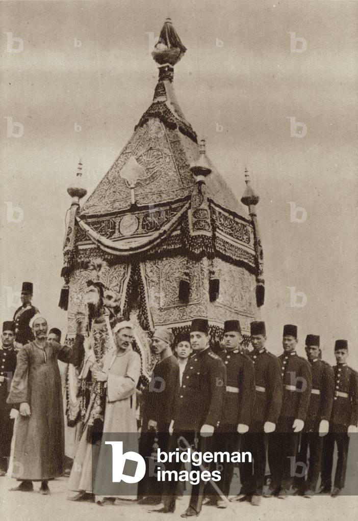 The Mahmal, holy carpet manufactured in Egypt to cover the Kaaba, being brought into the Grand Mosque, Cairo, on its return from Mecca (b/w photo)
