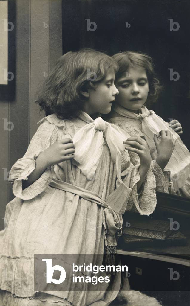 Girl looking at her reflection in a mirror (b/w photo)