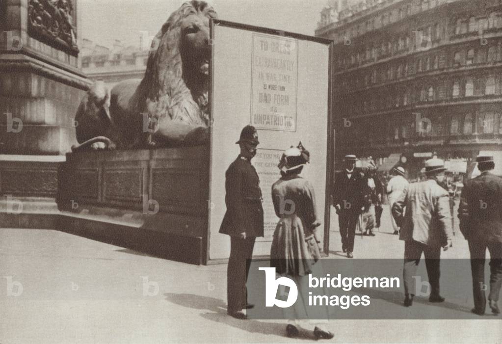 Poster in London's Trafalgar Square warning that dressing extravagantly is unpatriotic, First World War, 1916 (b/w photo)
