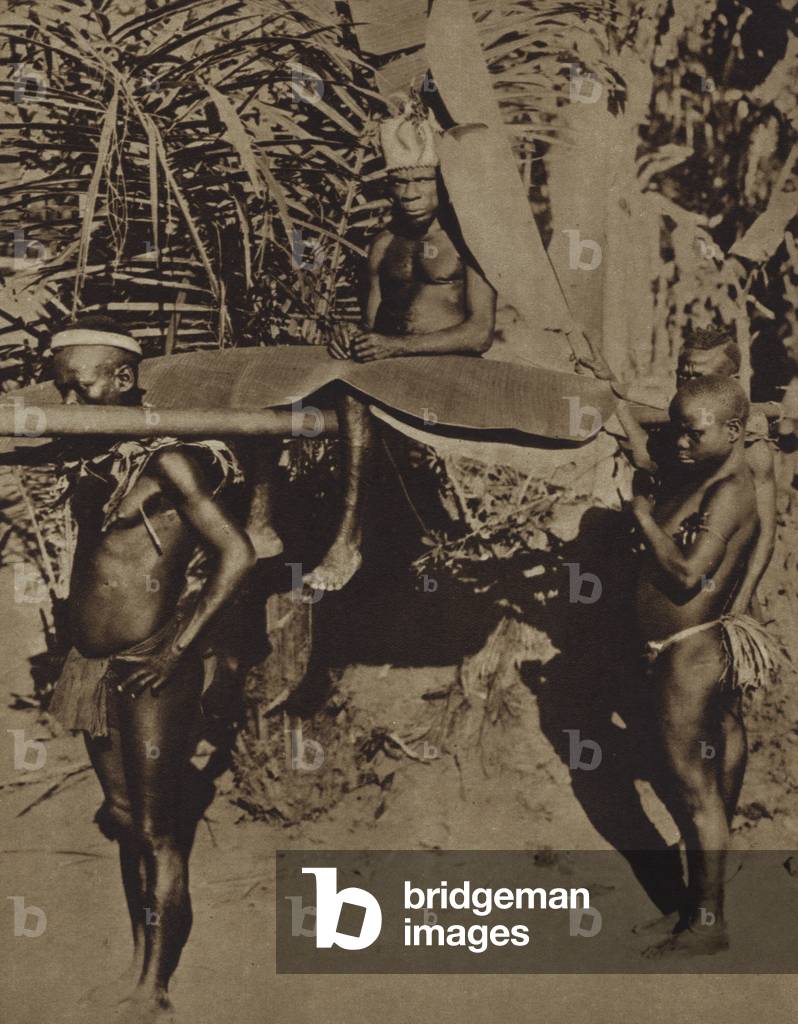 Chief of an African Pygmy tribe being carried on a litter (b/w photo)