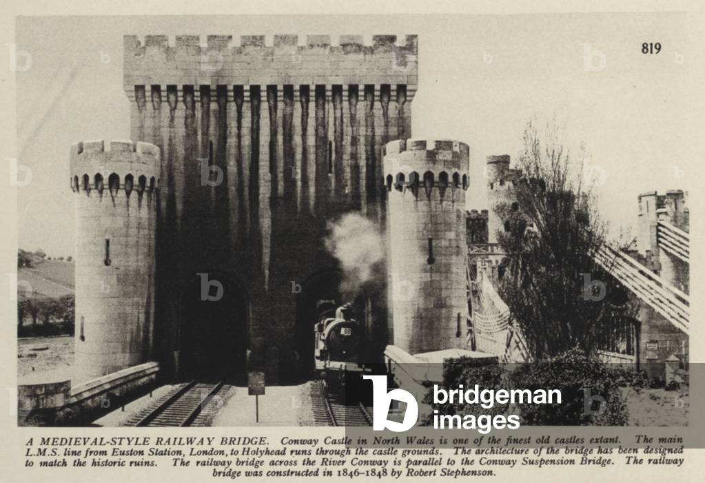 Train en route from London Euston to Holyead on the London, Midland and Scottish Railway crossing the Conwy Suspension Bridge in North Wales, built by Robert Stephenson in 1846-1848 (b/w photo)