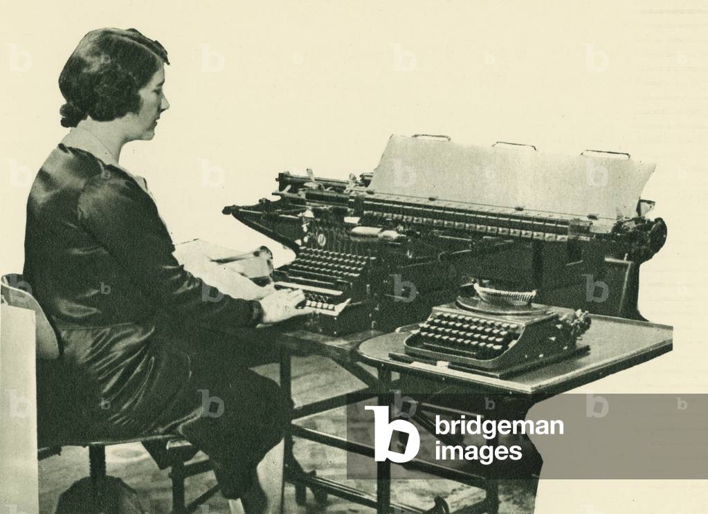 Woman using a typewriter for tabulating accounts (b/w photo)