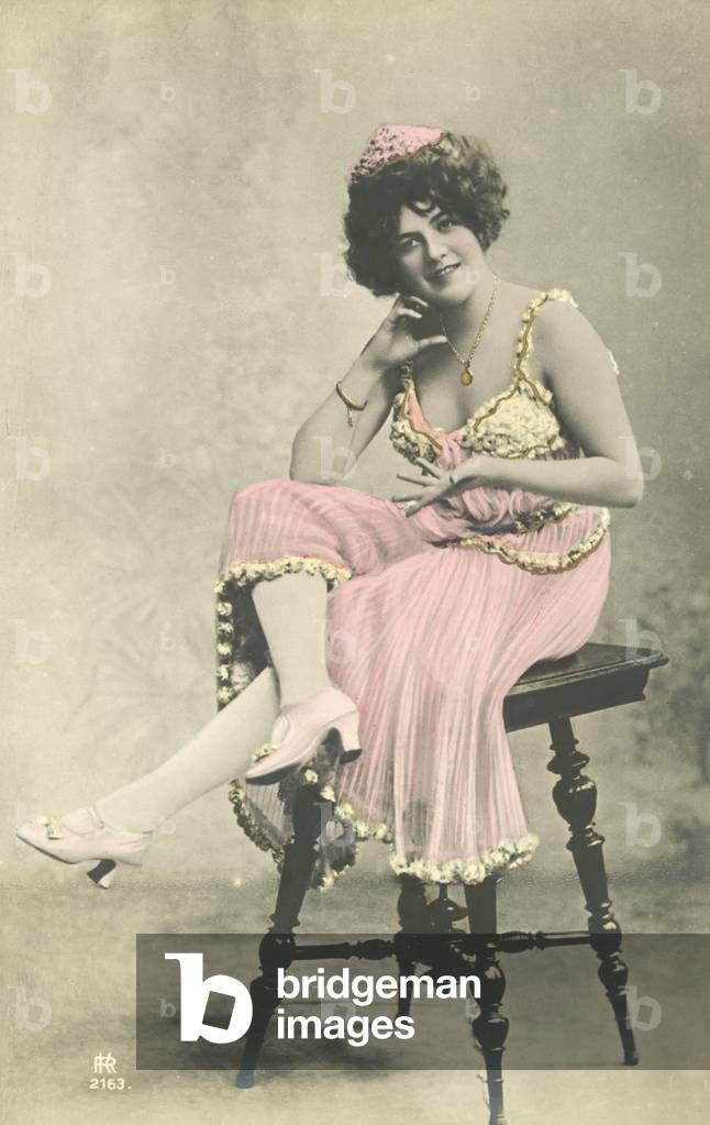 Actress, with nice smile, in pink dress sitting on stool (colour photo)