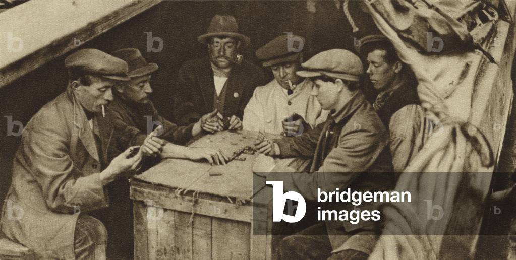 Bargee and his mates playing dominoes in the hold of a barge on a London canal (b/w photo)
