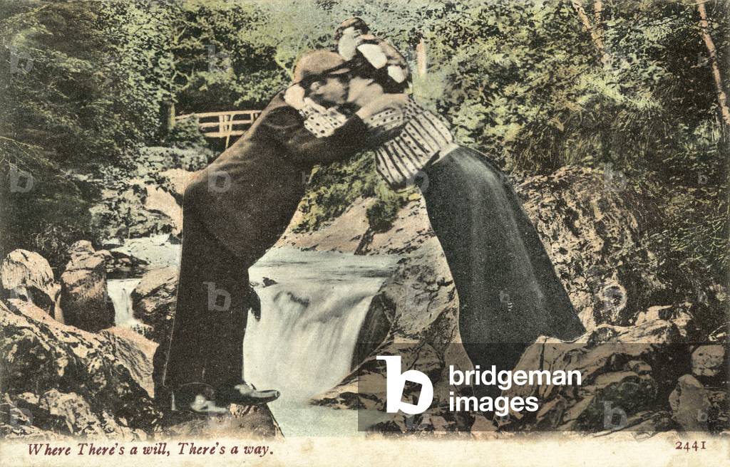 Couple kissing over stream, with waterfall behind (colour photo)