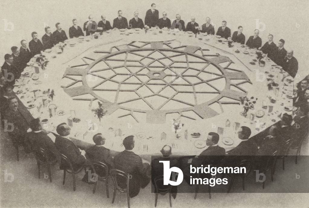 Large clock face made for a building in Liverpool being used as a dining table (b/w photo)