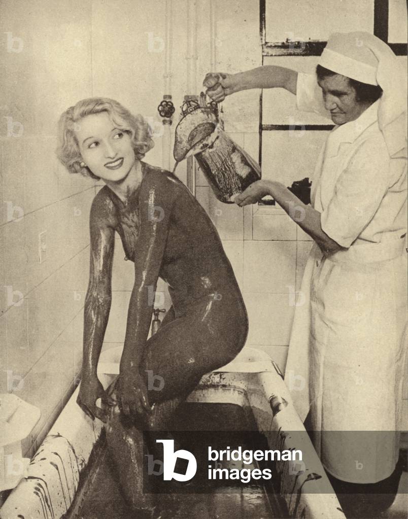 Woman having a mud bath treatment at a beauty salon (b/w photo)