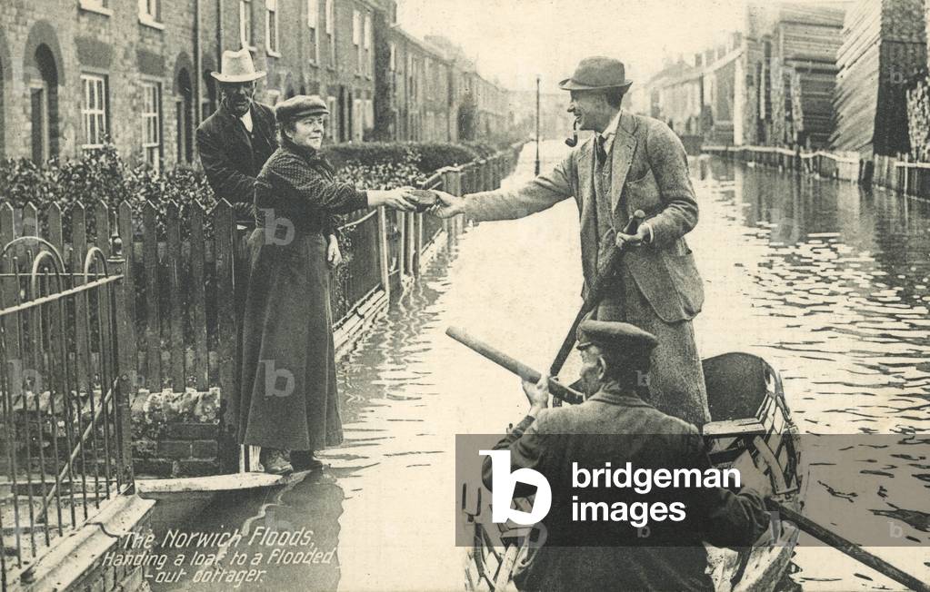 Flooded out cottager receiving a loaf of bread during the floods in Norwich, Norfolk, 1912 (b/w photo)