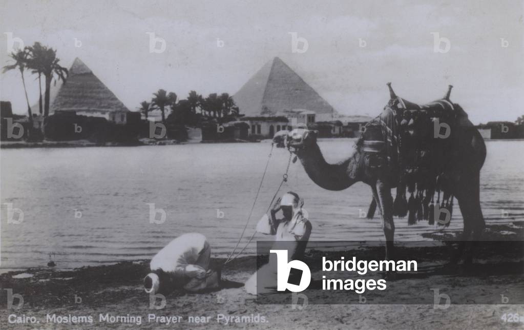 Muslims at morning prayer near the Pyramids in Cairo, Egypt (b/w photo)