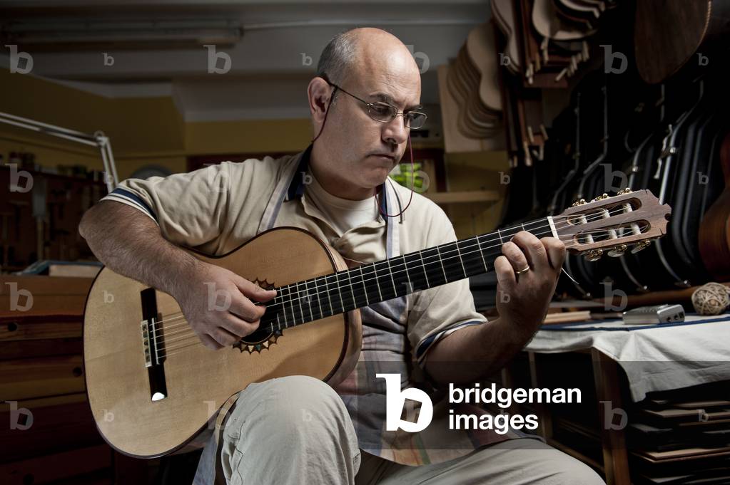 Master Luthier (Guitar-Maker) in his workshop in the process of making a classical Spanish guitar