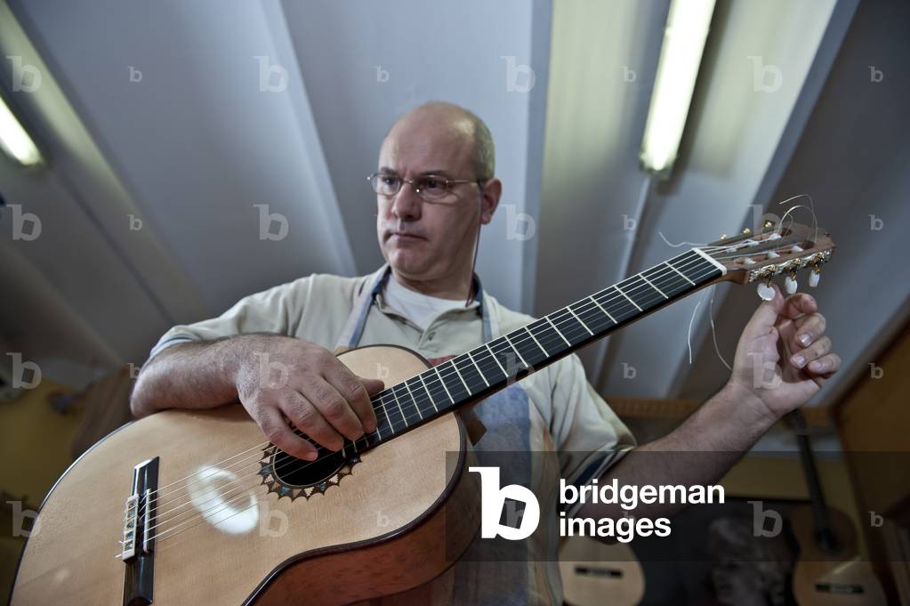 Master Luthier (Guitar-Maker) in his workshop in the process of making a classical Spanish guitar