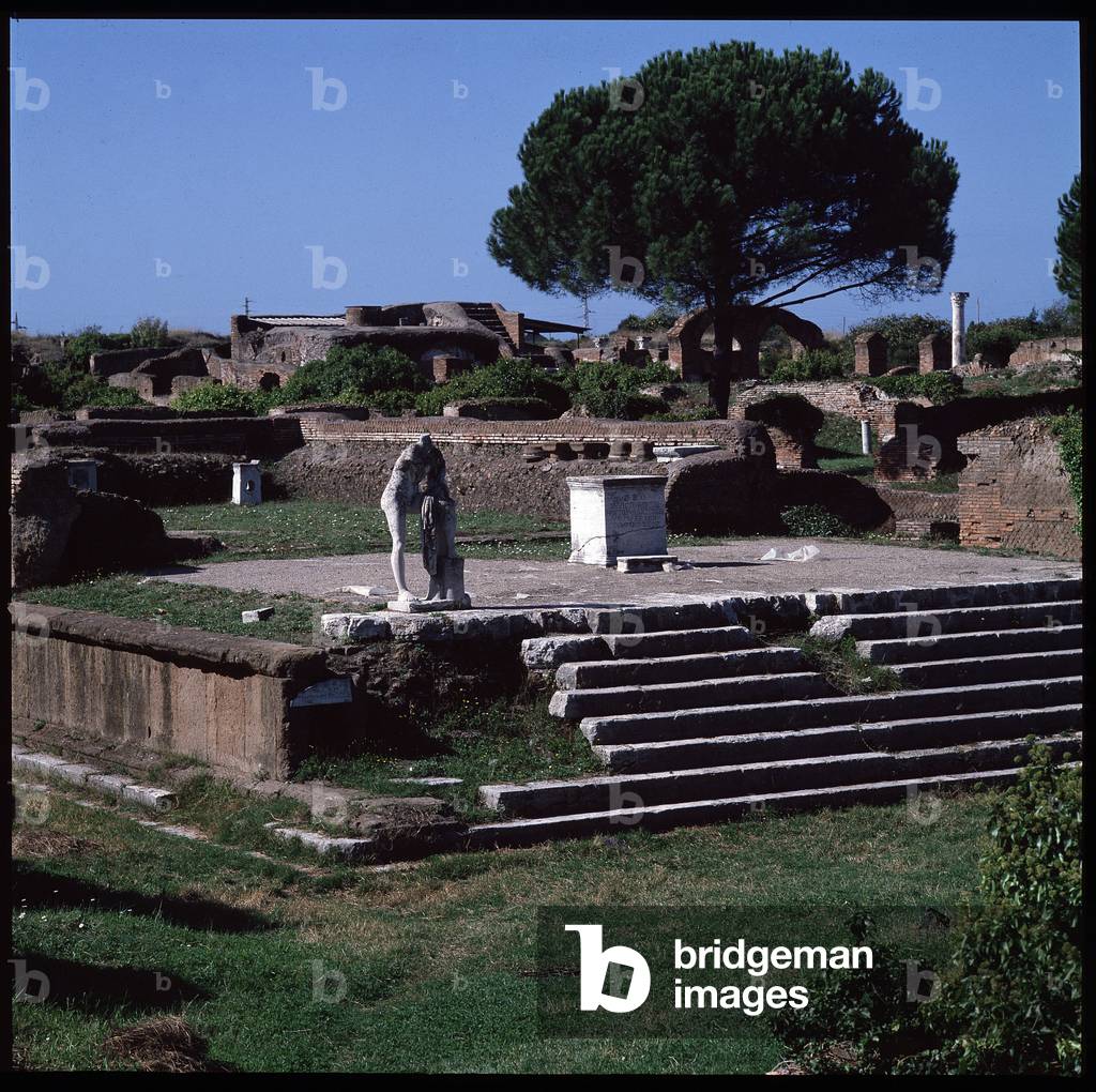 Roman art: view of the ruins of the temple of Hercules and statue of Gaius Cartilius Popplicola, citizen of Ostia, 1st century BC, Ostia antica, Italy (Roman art: view of the tempio di Ercole, 1st century BC Ostia antica, Italy) Photography