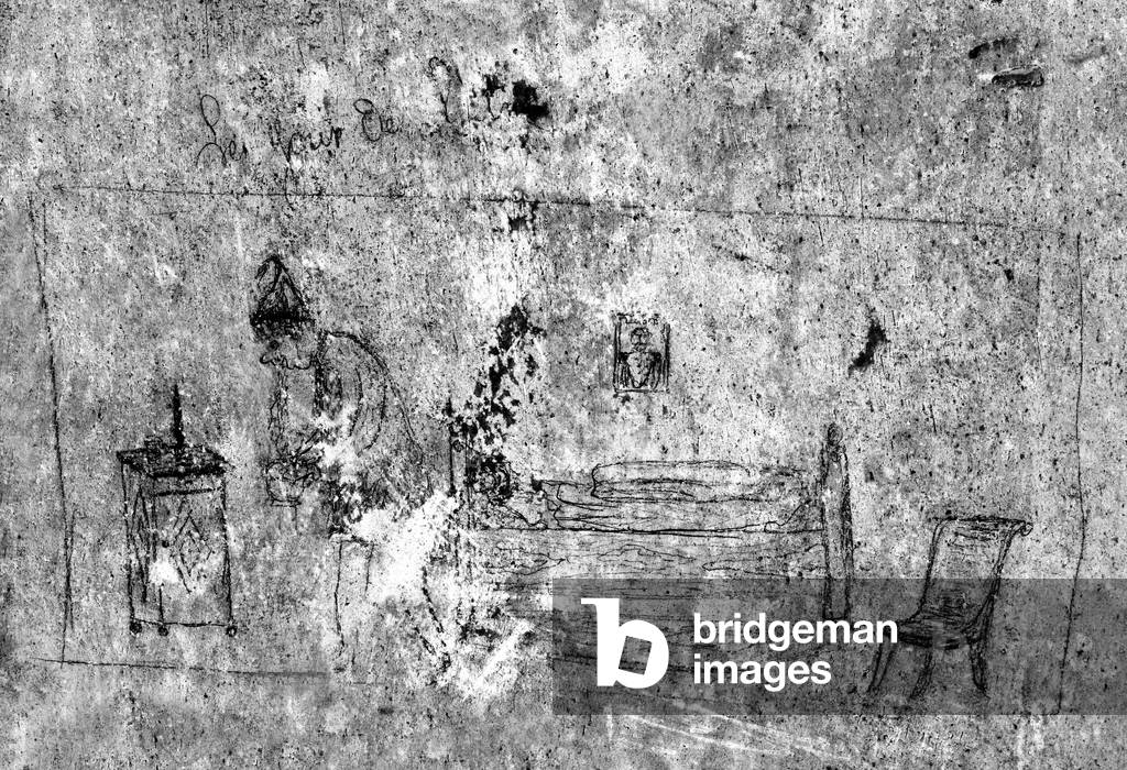 On New Year's Day, in a bedroom, a man, in pajamas and night cap, got up from his bed to vomit in his night vase; above his bed, a portrait of a legionary. Graffiti around 1873, on the wall of an apartment at 31 Clock Street in Sedan. Photography Leonard de Selva, France, 2008.