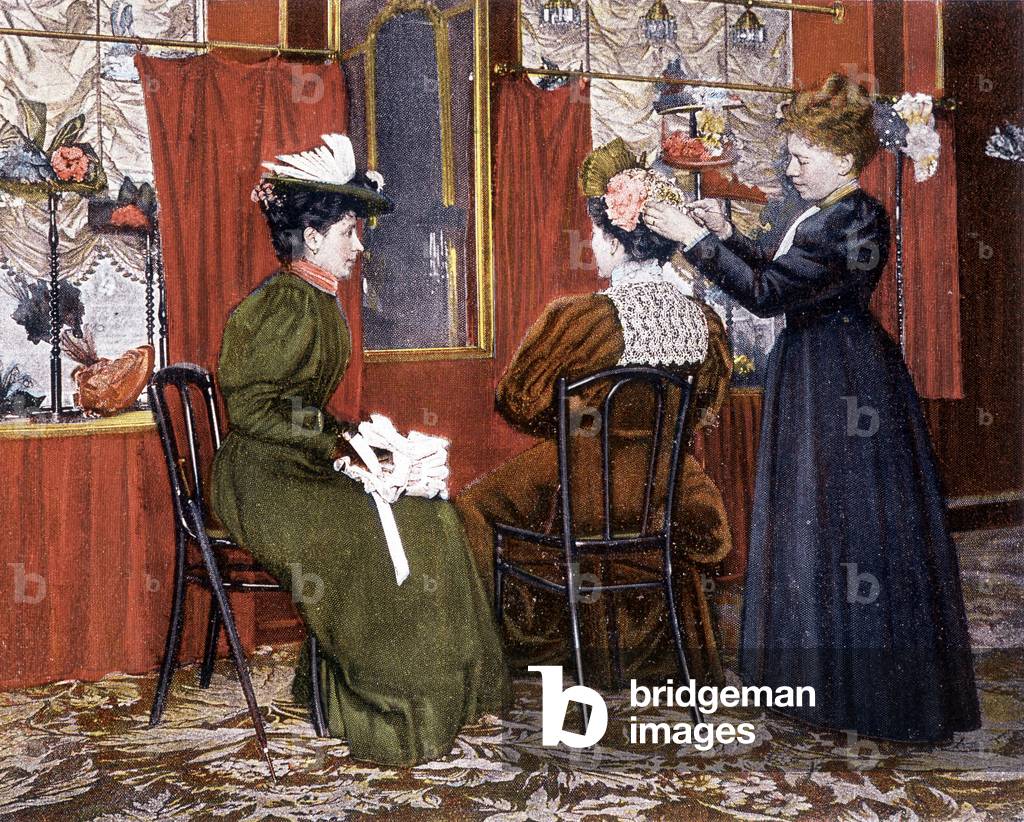 Woman styling a lady with a hat at the Maison Nouvelle, 1895.