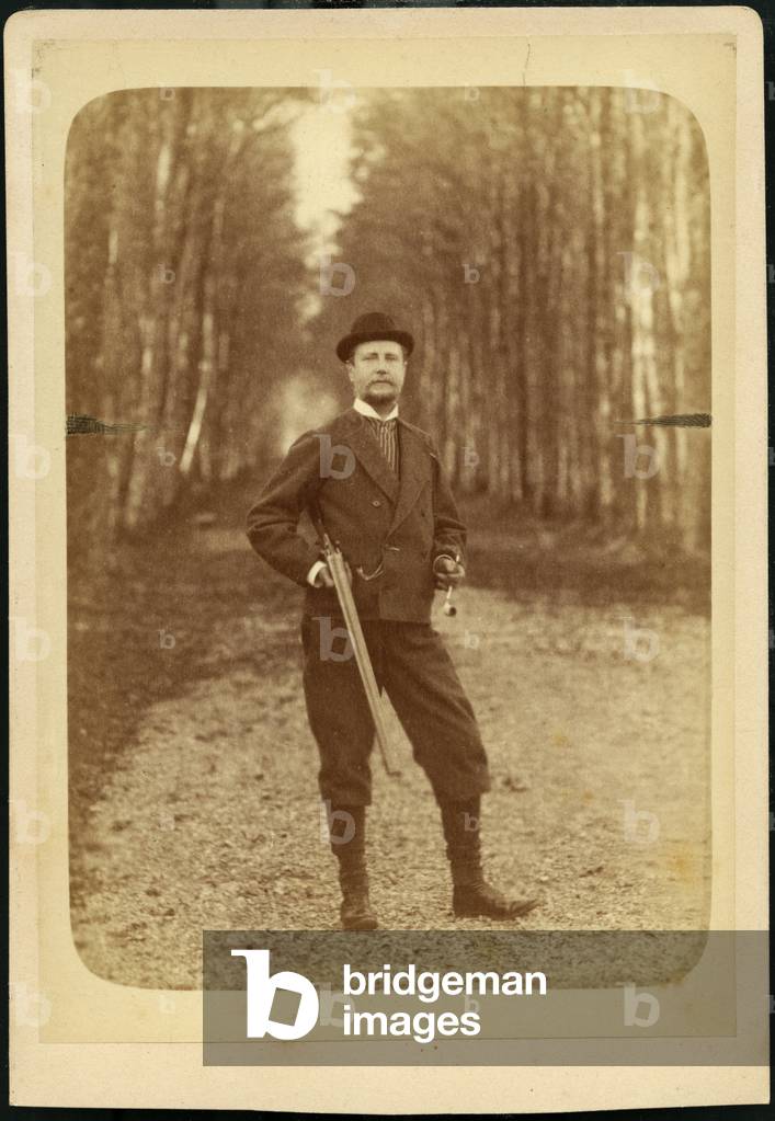A hunter with a pipe and a rifle, poses in his property, 1875