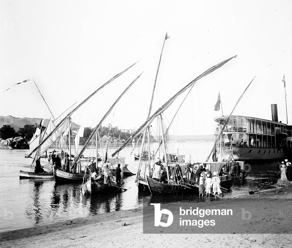 Egypt: Cook cruise, Nile village, Cook boat mooring on the bank, surrounded by felucks to take tourists to the temple of Philae, 1900