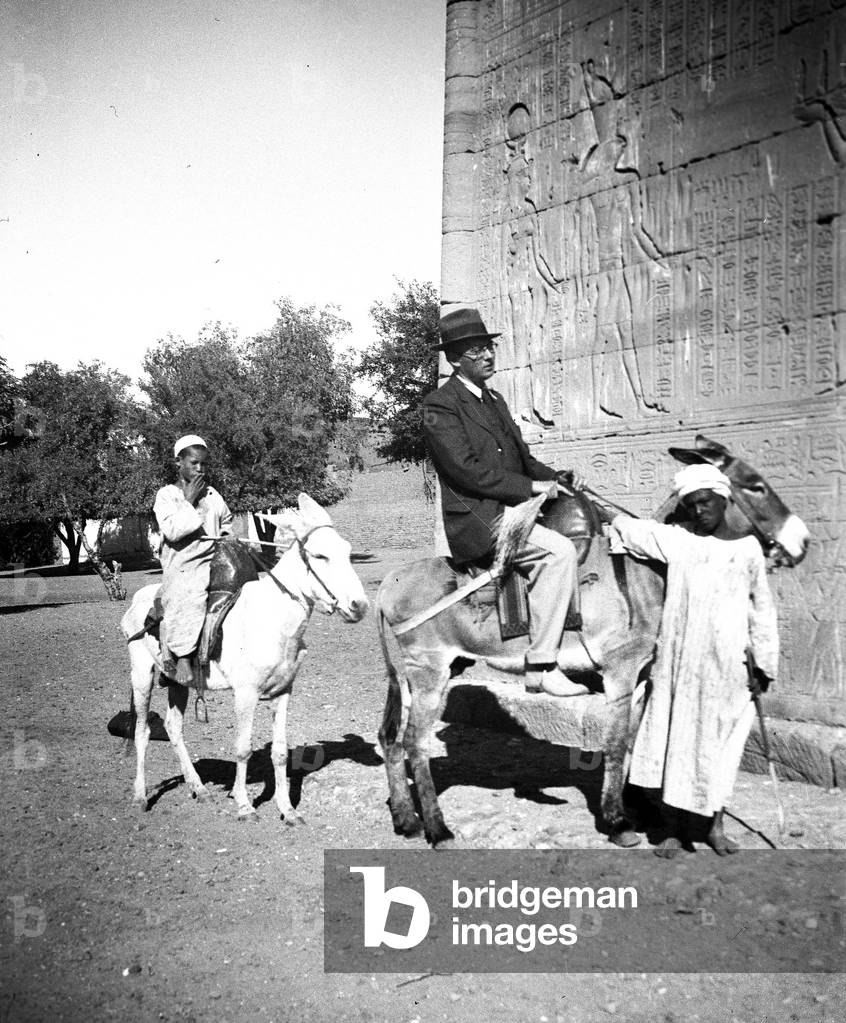 Egypt, Cairo: A European with donkey and accompanied by a guide in an Egyptian temple covered with hieroglyphs, 1930
