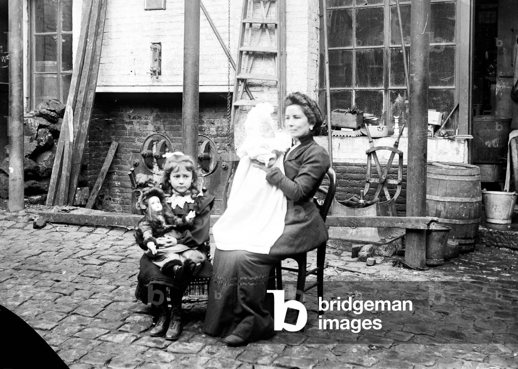France, Centre, Loiret (45), Orleans: forging workshop with outside a woman and her baby and a little girl and her doll, 1900
