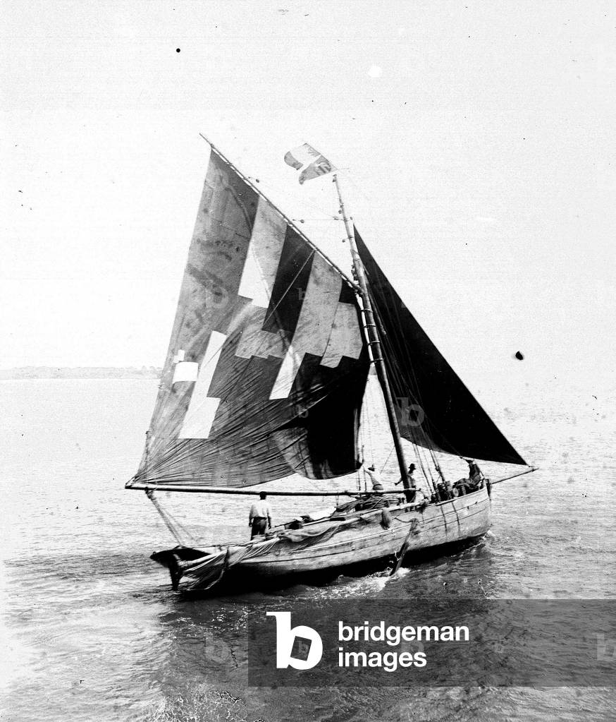 France, Bretagne : bateau de peche avec voile reprisee, aux larges des cotes, 1900 