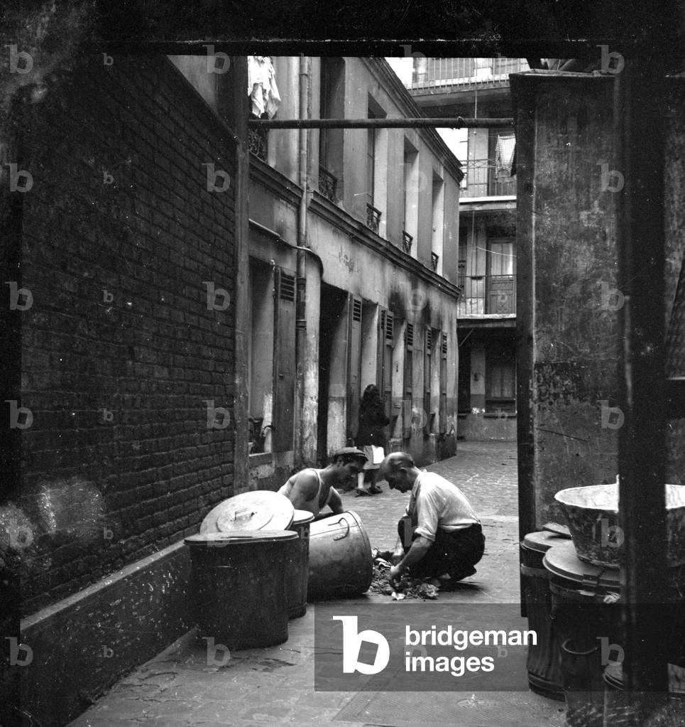 France, Ile-de-France, Paris (75): in a building yard, two men sort garbage, 1945