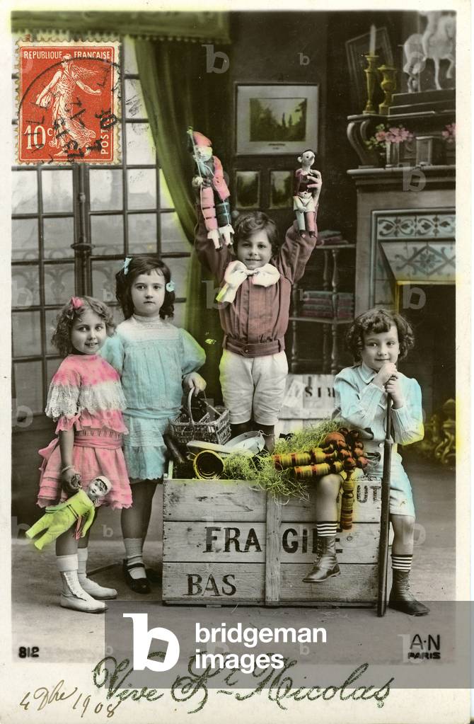France: Four children and their Christmas toys pose in front of the fireplace, 1908
