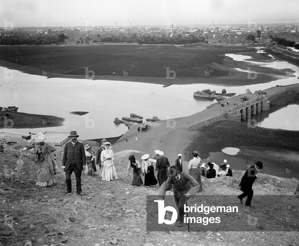 Egypt, Upper Egypt, Aswan: Cook cruise on the Nile, tourists climb the foothills of the pyramids in the suburbs near Cairo with in the background the flooded Nile plain as well as a bridge or pass a road leading to Cairo, 1900