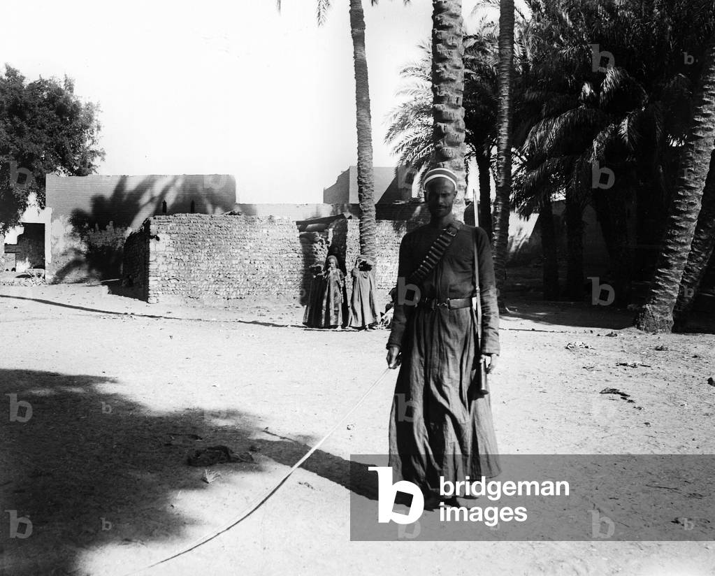 Egypt: Cook cruise on the Nile, in a home environment of land and palm trees, a man wearing a kind of uniform with a leather belt, a harness harness, a gun and a soft stick, 1900