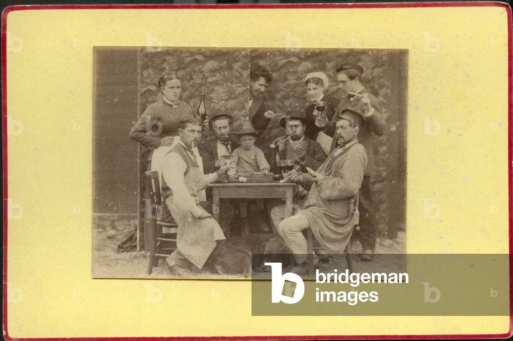 Workers and their families pose in studio with a recomposed scene of card game, 1870