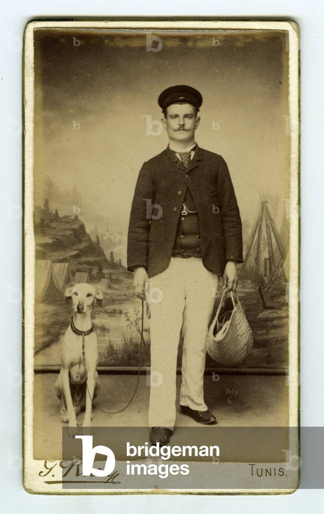 Tunis, Tunisia, A man and his dog pose in studio in front of a painted background, 1880