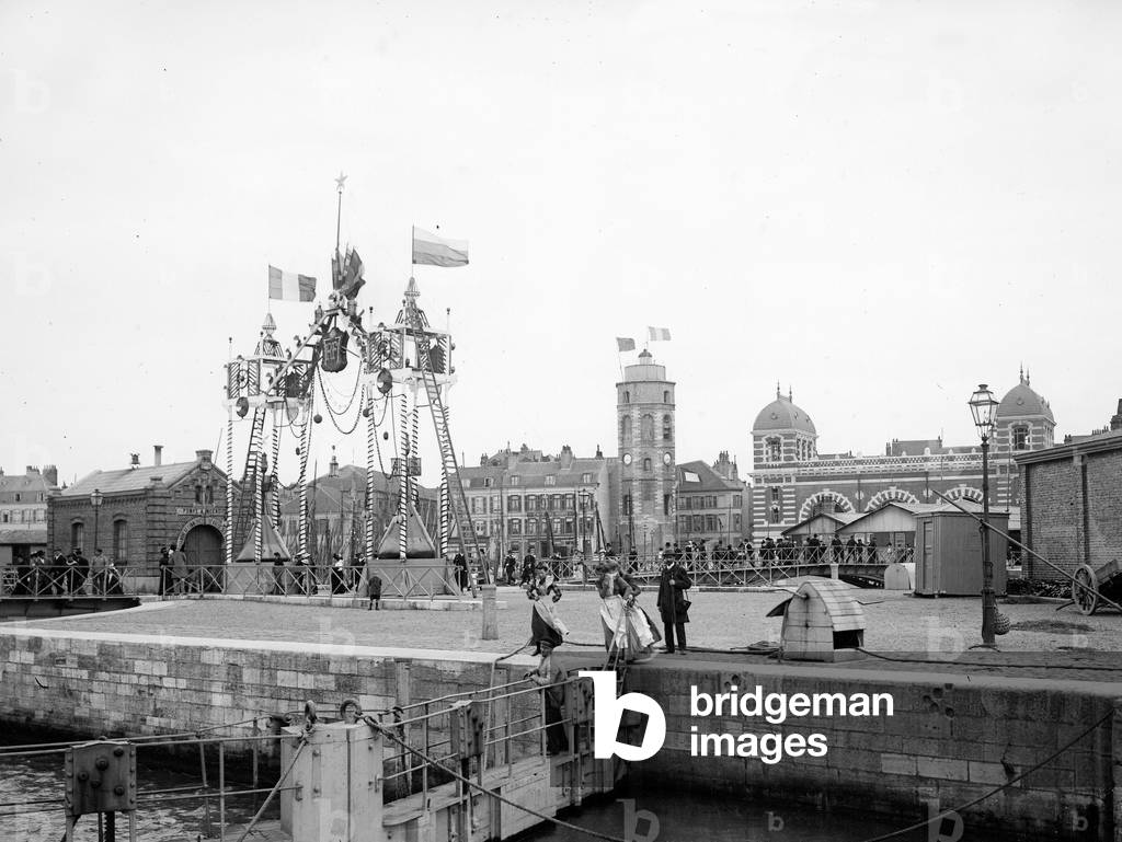 France, Nord-Pas-de-Calais, Nord (59), Dunkirk: party in a northern port with many curious coming to contemplate an arch made of different pieces of boats: bar, lantern, mats, pennants. Port bordered by brick architecture buildings, 1890