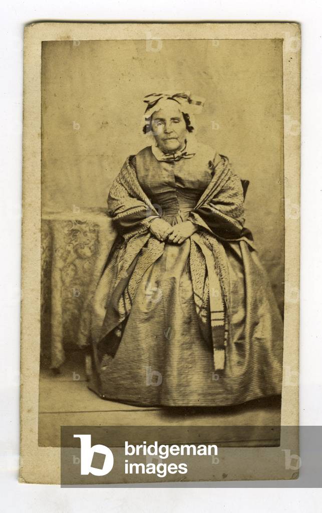 France, A woman poses in a studio in a traditional dress with headdress, 1860