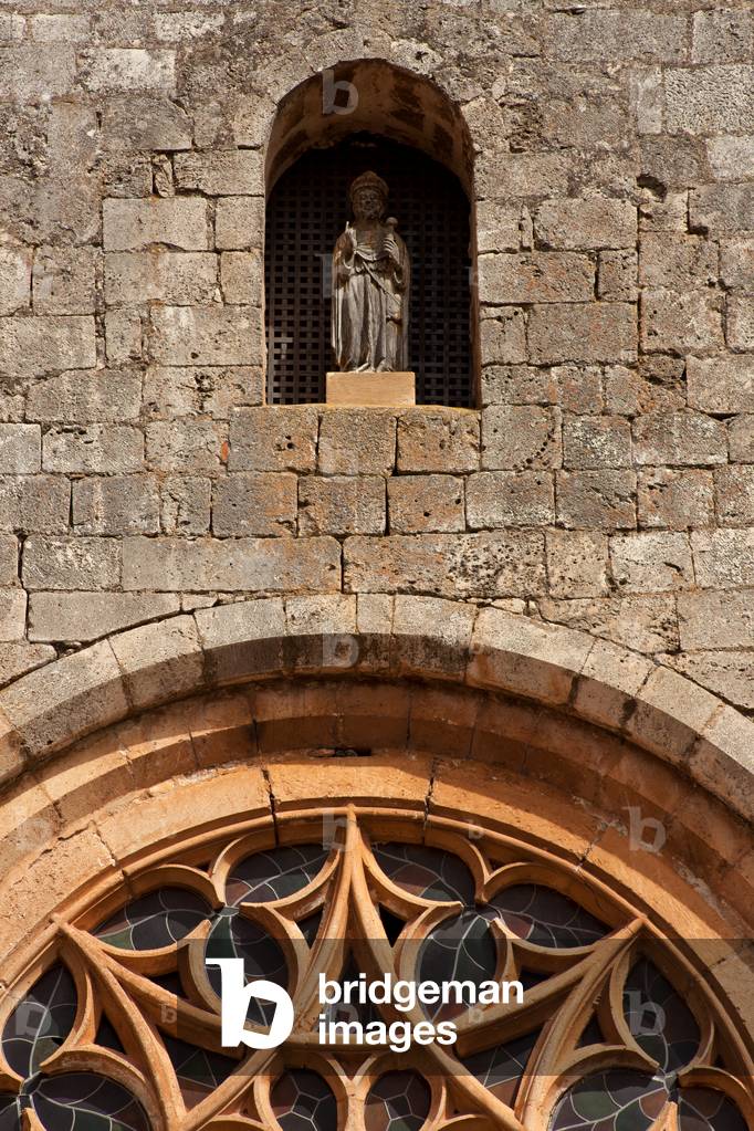 Colegiate church (Colegiata de San Cosme y San Damiàn de Covarrubias). Exterior. West façade. The rose window and a statue in a niche. A christ (?). Wood.