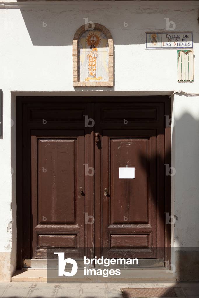 Calle de Nuestra Señora de las Nieves. Casa del Capellan de las Bernardas. A house door. A little praying chapel. Madonna and child on tiles. “Ntra Sra de las Nieves. Artesania Talaverana SL Alaver (?)”.