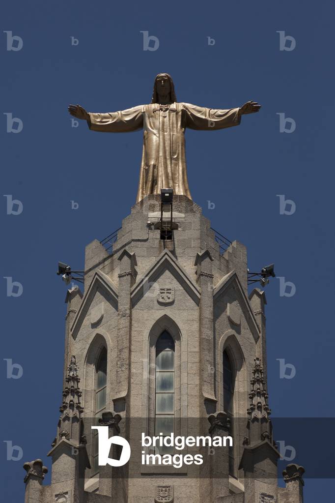 City site mount Tibidabo. The basilic church Holy hearth (Església de Sagrat Cor). Exterior. The façade. Detail the spire and the statue of Christ. Neo-Gothic.