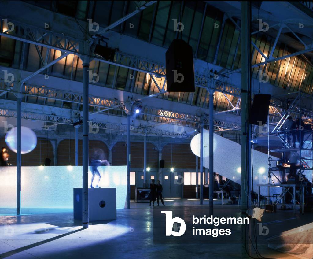 Location Unqiue in Nantes. Architecture by Patrick Bouchain, 2000. Photography 2000. Destined for the manufacture of biscuits, the Lefevre-Utile factory was built at the beginning of the 20th century on the edge of the Saint-Felix Canal using modern techniques. Two Art Nouveau towers designed by Auguste Bluysen were added in 1909. The workshops were active until the beginning of the 1970s and in 1986 the factory was definitively closed. The tower was restored in 1998 by Jean-Marie Lepinay. And Patrick Bouchain will carry out the renovation while keeping the spirit of the place, that of a factory spontaneously transformed into a cultural place. Unique Place Exhibition Hall
