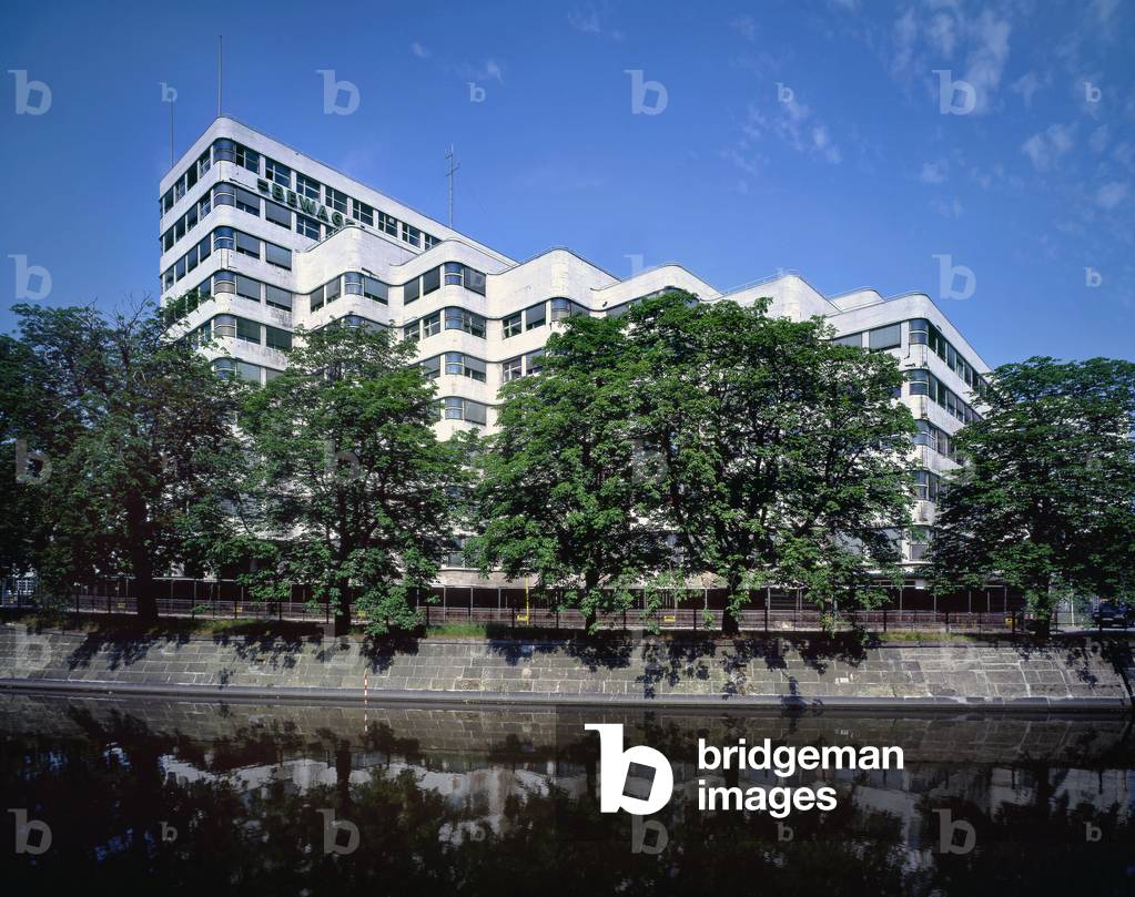 Shellhaus, Tiergarten to Berlin (Germany). Before he could build this office building, which had the revolutionary look of the period, the architect Emil Fahrenkamp had to review his plans almost three hundred times before the town planning commission gave its approval in 1930. In 1931, Shell House was inaugurated. Its undulating facade in decrochees was born thanks to the use of a metal frame, a first in Berlin. The dynamic wing, visible to the Landwehrkanus, has a height of five levels in its lower part, gradually reaching ten. Damaged during World War II, the Shell House underwent successive restoration work, respecting its historical aspect and the original interior fittings. In 1965-1968, two towers designed by Paul Baumgarten were added to him on his North wing. The final work took place from 1997 to 1999, and enabled the Berlin gas company, GASAG, to set up its headquarters there.