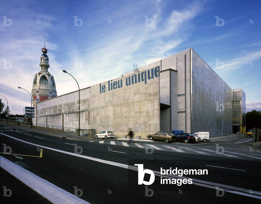 The Unique Place in Nantes. Architecture of Patrick Bouchain 2000. Destined for the manufacture of biscuits, the Lefevre-Utile factory was built at the beginning of the 20th century on the edge of the Saint-Felix Canal using modern techniques. Two Art Nouveau towers designed by Auguste Bluysen were added in 1909. The workshops were active until the beginning of the 1970s and in 1986 the factory was definitively closed. The tower was restored in 1998 by Jean-Marie Lepinay. And Patrick Bouchain will carry out the renovation while keeping the spirit of the place, that of a factory spontaneously transformed into a cultural place.