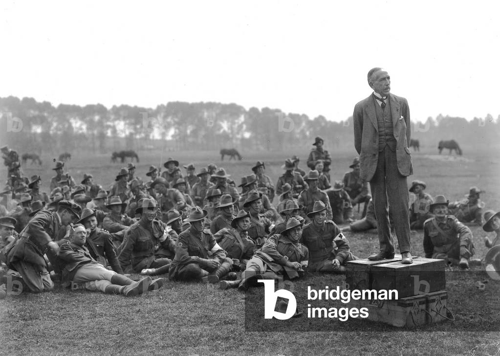 The Right Honourable William Morris (Billy) Hughes, standing on a platform composed of four ammunition boxes, addressing a gathering of the 5th Australian Field Ambulance, near La Motte about one kilometre from Camon, 3 July 1918 (b/w photo)