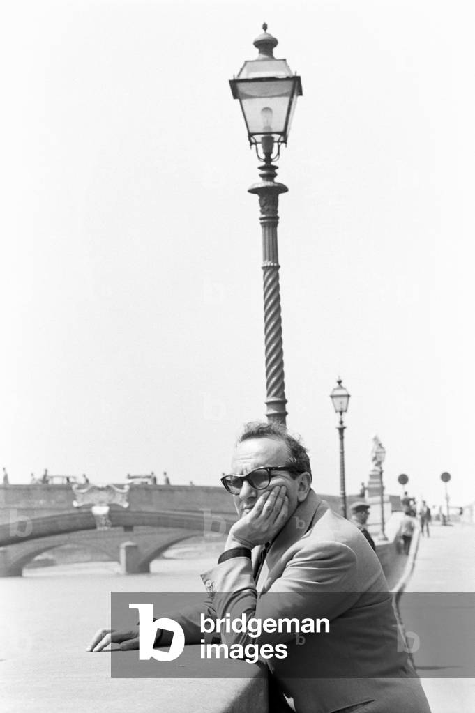 Vasco Pratolini rests against a parapet overlooking the Arno River