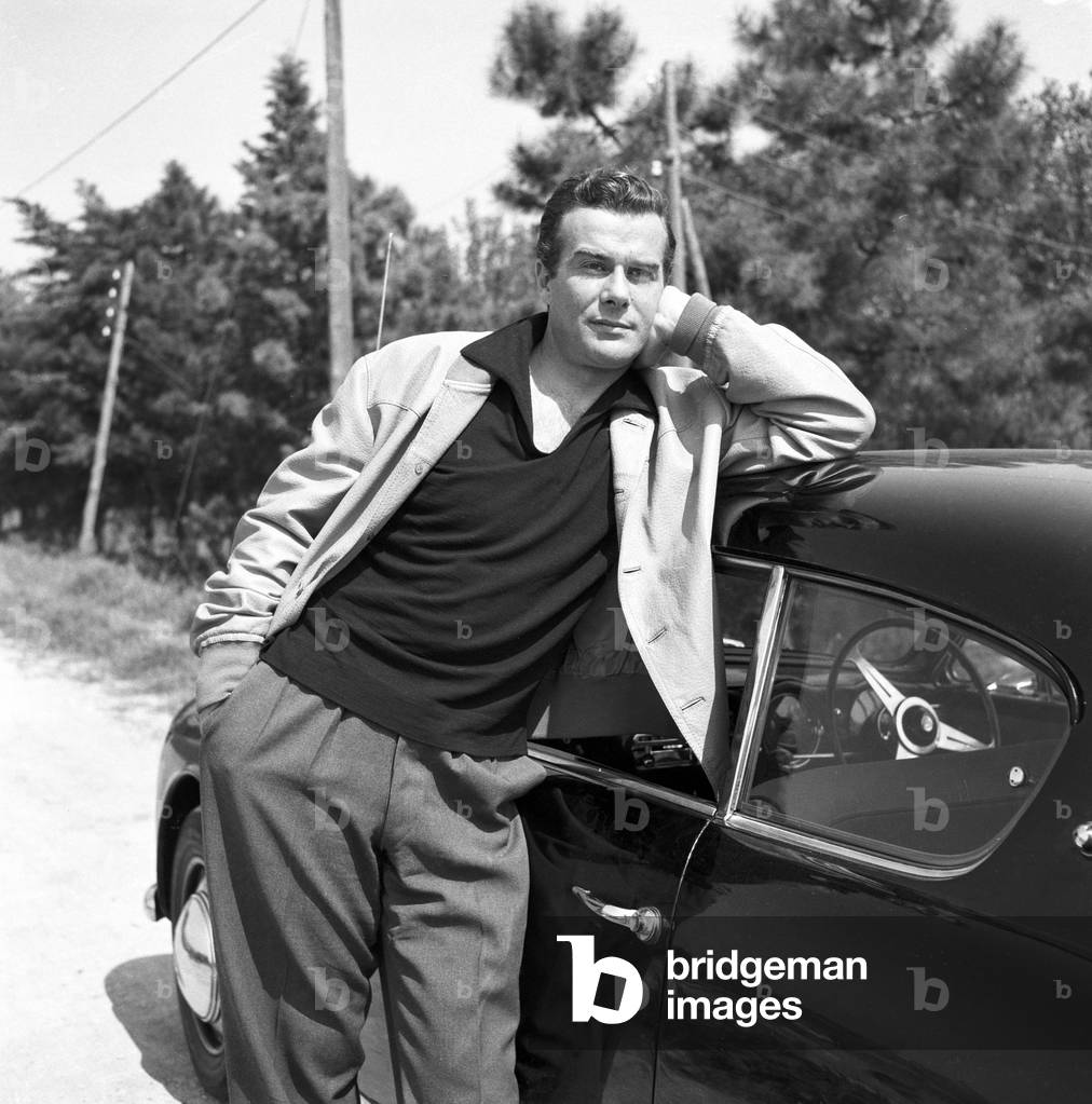 Massimo Serato leaning against his car, Italy, 1957 (b/w photo)