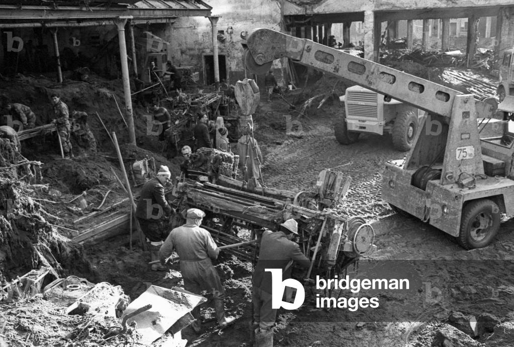 Some men moving the rubbles after a flood in the district of Biella, Italy, 1968 (b/w photo)