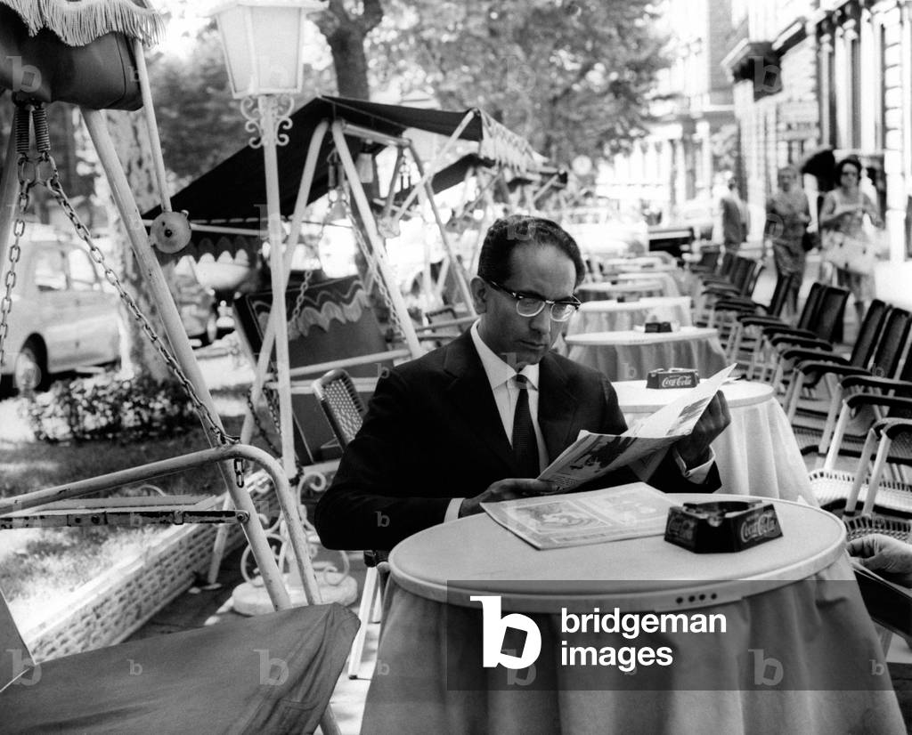 Emilio Colombo reads at a small table at a bar
