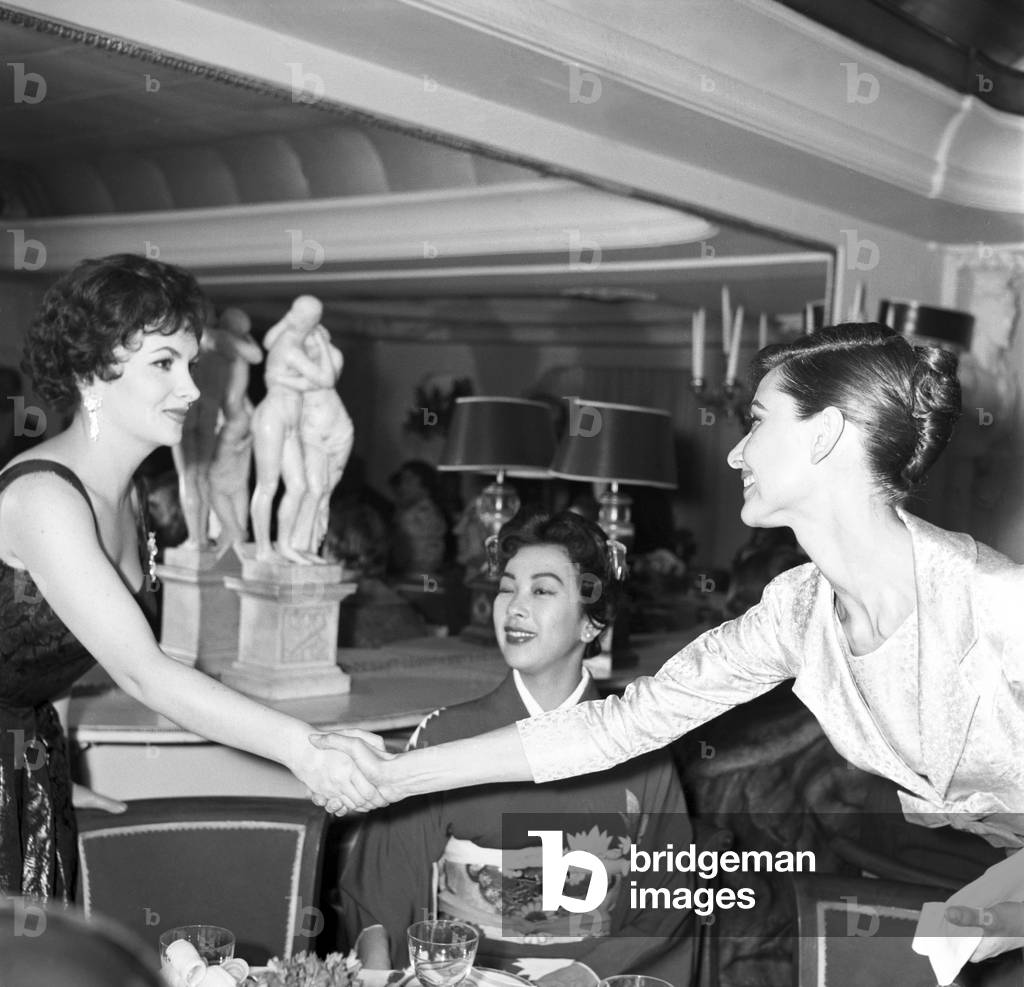 Miiko Taka looking at Audrey Hepburn and Gina Lollobrigida shaking hands, Italy, 1958 (b/w photo)
