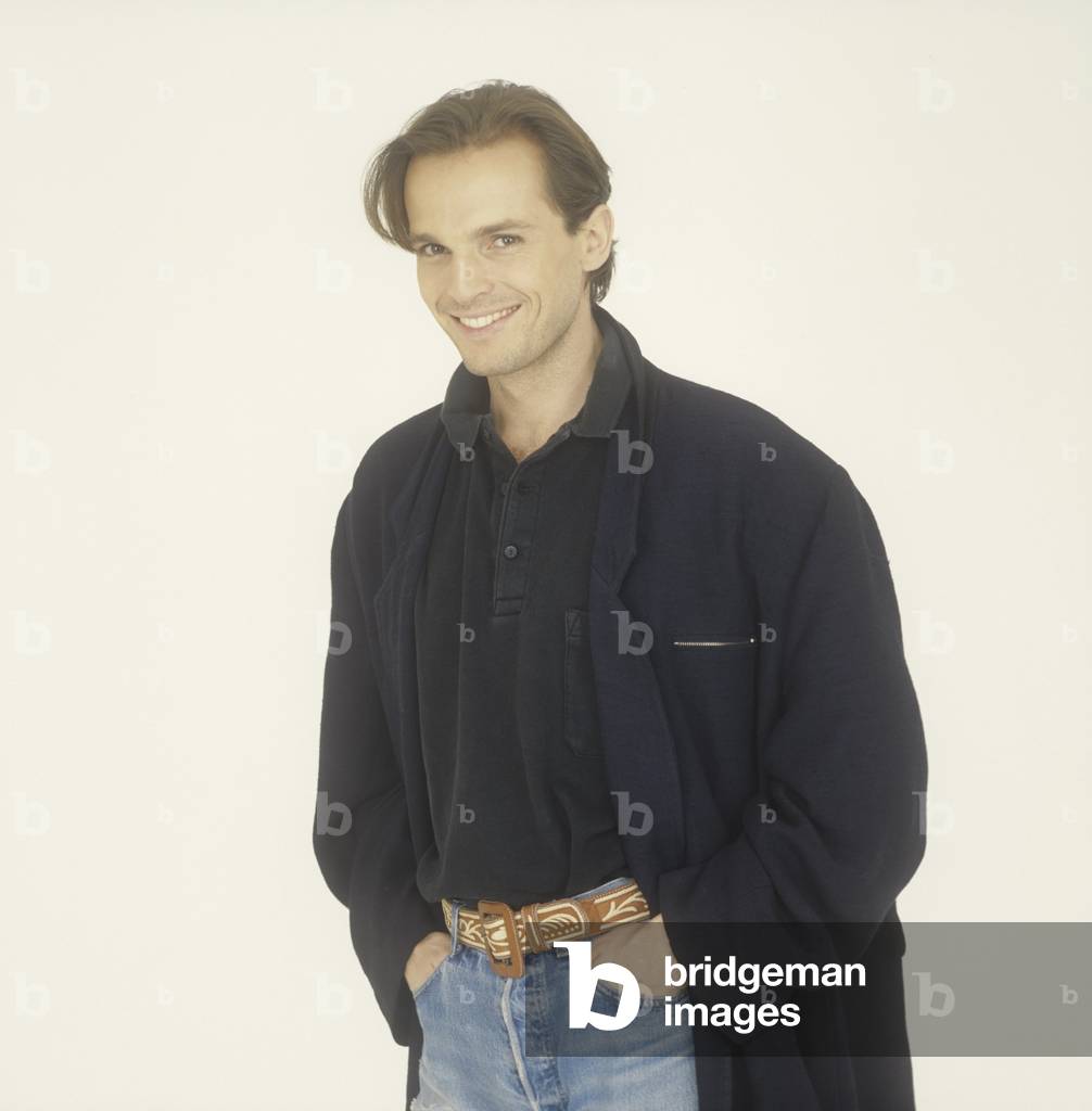 Miguel Bosé smiling in a raincoat, Italy