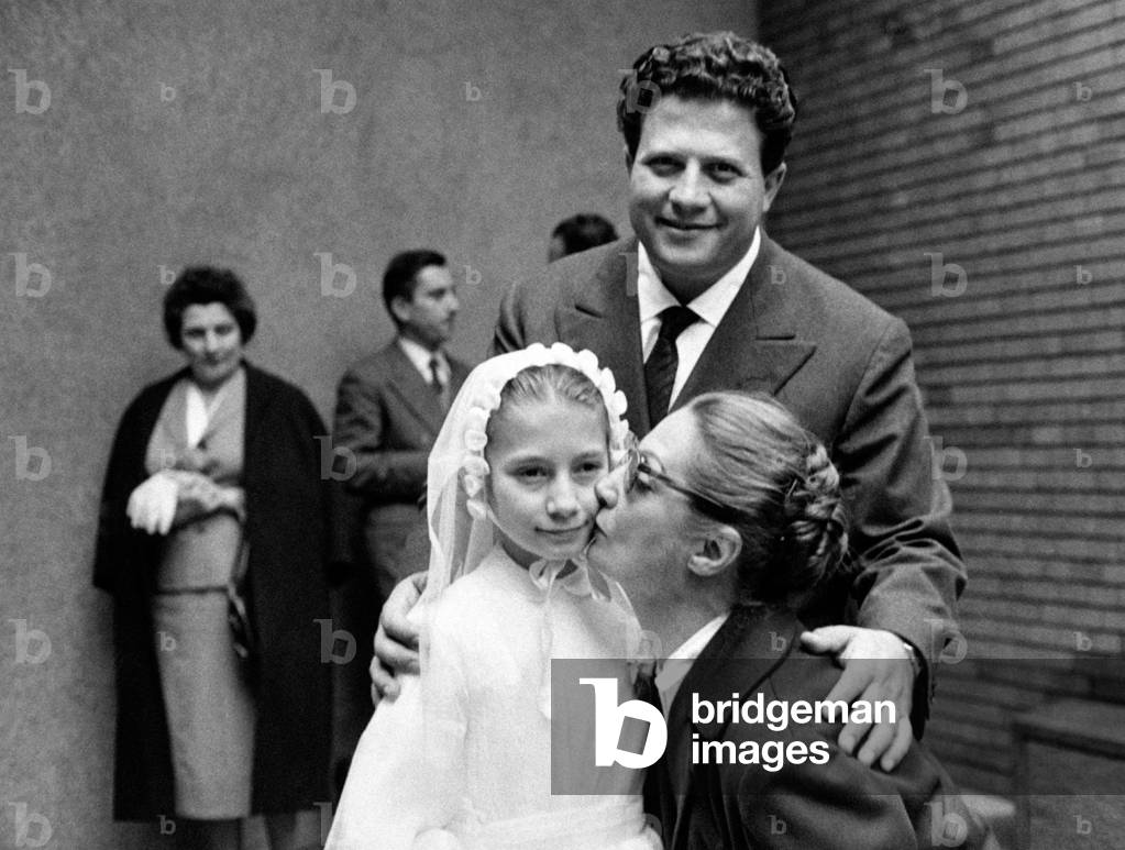 Sarah Ferrati kissing Monica Infantino at her holy communion with Luigi Infantino